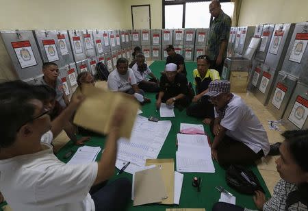 Election commission official Dedi Saidi (L) checks a document stating the number of votes collected in ballot boxes, at Bendungan Hilir in Jakarta, in this July 10, 2014 file photo. REUTERS/Beawiharta/Files
