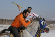 A rider is about to throw the javelin during a game of Cirit, a traditional Turkish equestrian sport that dates back to the martial horsemen who spearheaded the historical conquests of central Asia's Turkic tribes, between the Comrades and the Experts local sporting clubs, in Erzurum, eastern Turkey, Friday, March 5, 2021. The game that was developed more than a 1,000 years ago, revolves around a rider trying to spear his or her opponent with a "javelin" - these days, a rubber-tipped, 100 centimeter (40 inch) length of wood. A rider from each opposing team, which can number up to a dozen players, face each other, alternately acting as the thrower and the rider being chased. Cirit was popular within the Ottoman empire, before it was banned as in the early 19th century. However, its popularity returned as is now one of many traditional sports encouraged by the government and tournaments are often arranged during festivals or to celebrate weddings. (AP Photo/Kenan Asyali)