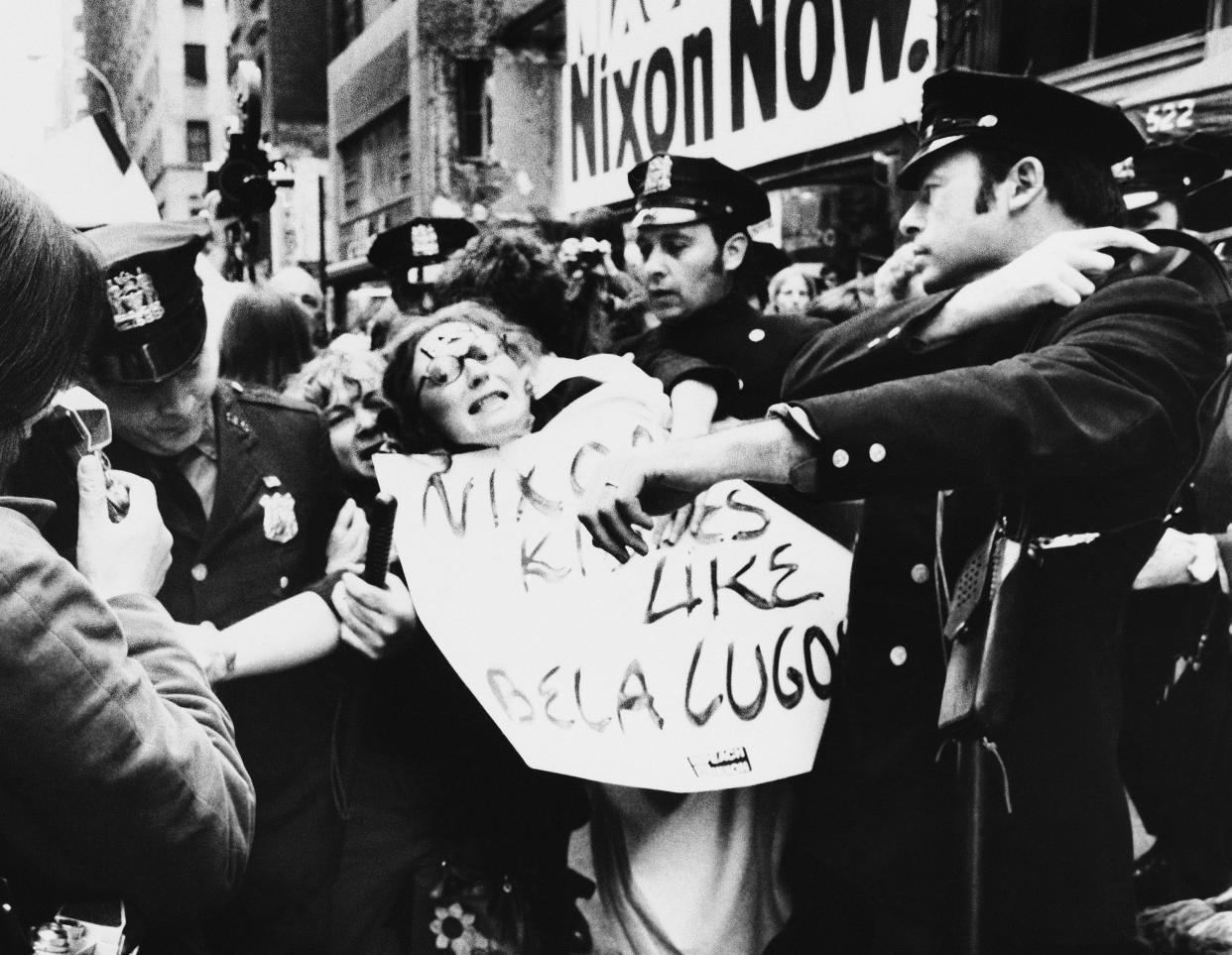 Ti-Grace Atkinson, a leader in the feminist movement, wearing sign, is taken into custody outside President Richard Nixon's campaign headquarters in New York on Oct. 23, 1972, after police said she and other demonstrators were blocking sidewalks and traffic. She and other women's rights advocates were protesting the president's positions on child care and abortion when the incident occurred. 