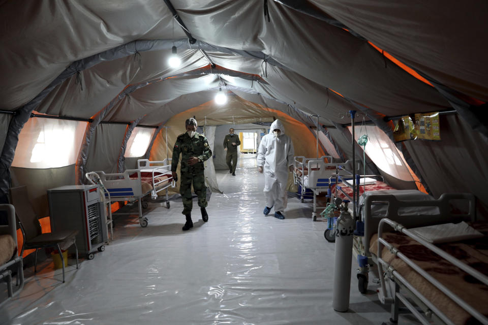 FILE - In this March 26, 2020 file photo, Iranian army soldiers work in a temporary 2,000-bed hospital for coronavirus patients set up by the army at the International Exhibition Center in northern Tehran, Iran. Dozens of medical staffers have died of COVID-19 in Iran. Doctors and nurses and other staffers have been hard hit. During the first 90 days of the virus outbreak alone, about one medical staffer died each day. (AP Photo/Ebrahim Noroozi, File)