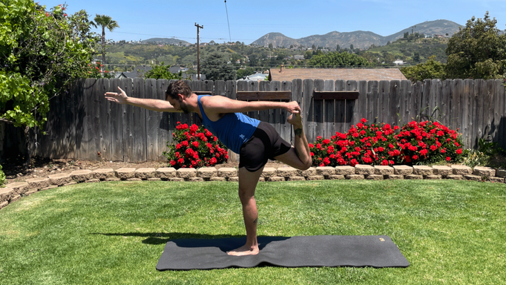 Man outside in his back yard practicing yoga for tall people on a mat