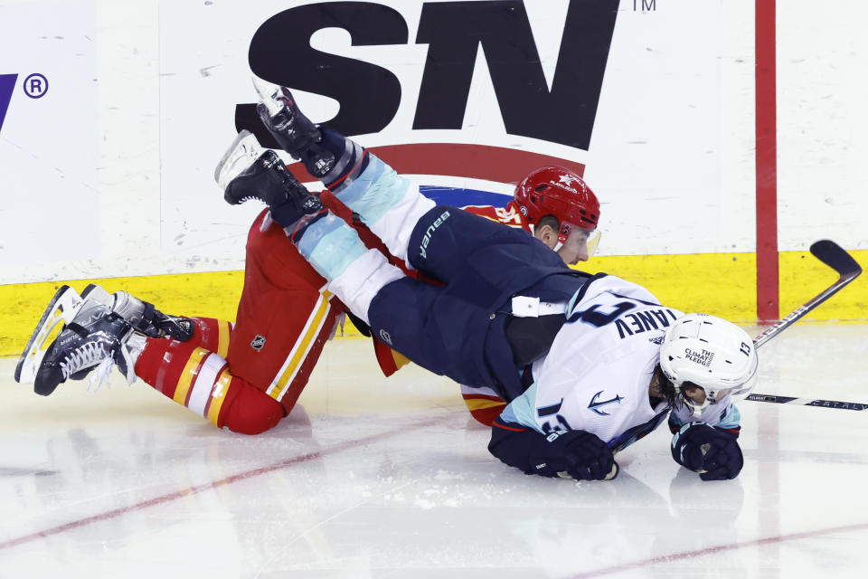 Seattle Kraken's Brandon Tanev, right, falls over Calgary Flames' Dennis Gilbert during the second period of an NHL hockey game Wednesday, Dec. 27, 2023, in Calgary, Alberta. (Larry MacDougal/The Canadian Press via AP)