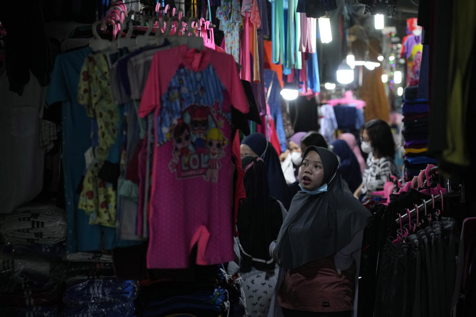 Una mujer observa ropa exhibida en un mercado en Yakarta, Indonesia, el 14 de agosto de 2022. (AP Foto/Achmad Ibrahim)