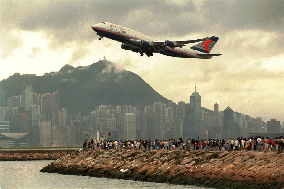 1998年7月5日，香港啟德機場跑道旁邊的海港，大批人群聚集在海堤上，觀看最後一架飛機離開機場。