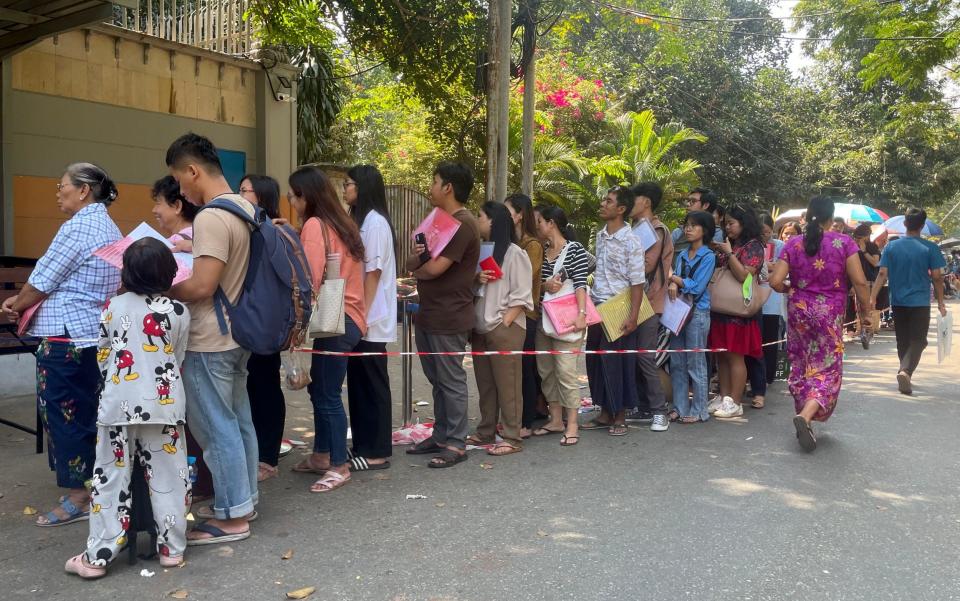 People queue for a token to apply for a visa outside the Royal Thai embassy in Yangon, Myanmar on Friday