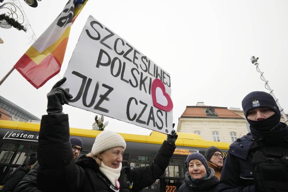 People greet Polish Prime Minister Donald Tusk with a poster saying "Happy Poland. It's Time" as he and his ministers arrive to be sworn in at the presidential palace in Warsaw, Poland, Wednesday Dec. 13, 2023. The swearing-in ceremony marked the end of eight tumultuous years of rule by a national conservative party, Law and Justice, and the ascent of Tusk's pro-European Union administration, which vows to respect constitutional norms and be a steady Western ally and a strong European leader. (AP Photo/Czarek Sokolowski)