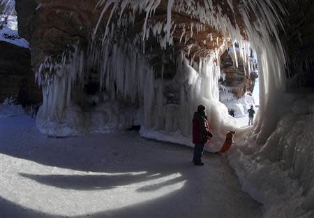 Pete Miller, from Minong, Wisconsin looks through an opening with his dog Max Sightseers at the sea caves of the Apostle Islands National Lakeshore of Lake Superior near Cornucopia, Wisconsin February 14, 2014. REUTERS/Eric Miller
