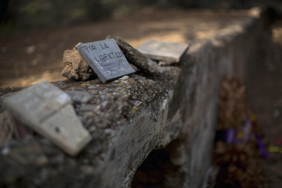 In this Tuesday, Aug. 28, 2018 photo, an inscription written on a stone reads in Spanish "For the freedom" at a wall called "El Paredon" where people were allegedly executed by General Franco's regime, close to the cemetery of Paterna, near Valencia, Spain. Archaeologists are conducting forensic analysis of the human remains from a nearby mass grave, including DNA tests in the hope of confirming the identities of those who disappeared eight decades ago, believed to have been executed by the forces of Gen. Francisco Franco during and after the 1936-39 Spanish Civil War. (AP Photo/Emilio Morenatti)