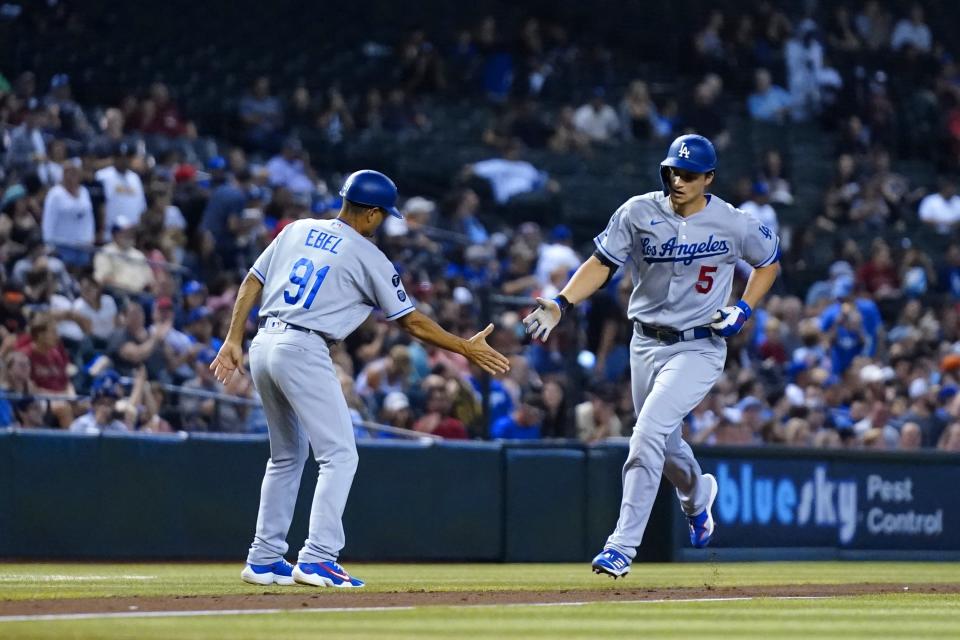 Los Angeles Dodgers' Corey Seager (5) shakes hands with Dodgers third base coach Dino Ebel (91) as Seager rounds the bases after hitting a home run against the Arizona Diamondbacks during the third inning of a baseball game, Sunday, Sept. 26, 2021, in Phoenix. (AP Photo/Ross D. Franklin)