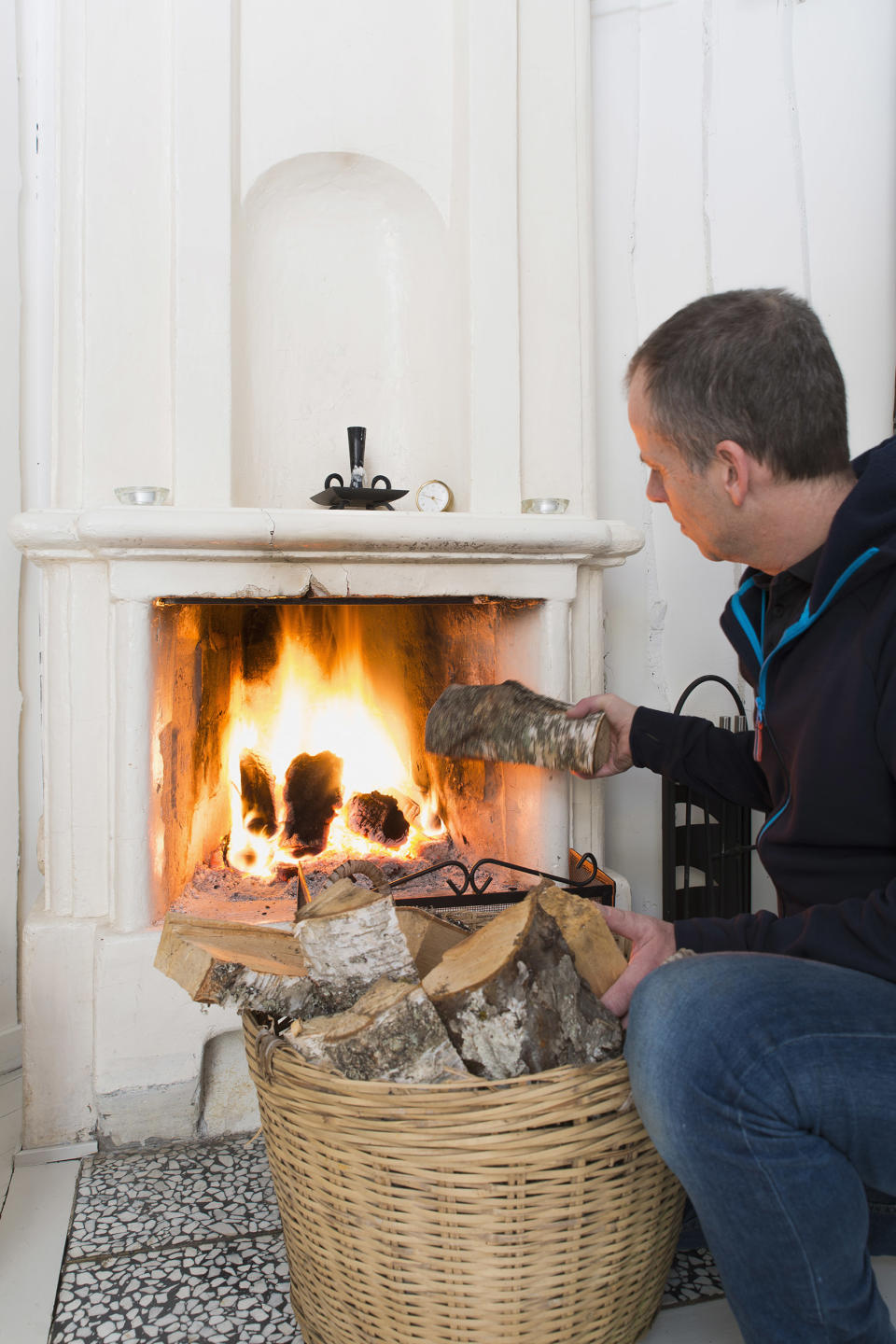 Man putting wood in fireplace (Johner Images / Getty Images)