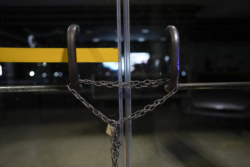 A chain lock reinforces the locked door of a gas station that started closing shop at night after the killing of a worker at a nearby station a few weeks before, in Rosario, Argentina, Monday, April 8, 2024. The order to kill came from inside Ezeiza Prison from gang leaders who hired a 15-year-old hitman to kill gas station worker Bruno Bussanich on March 9. (AP Photo/Natacha Pisarenko)