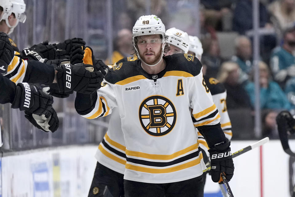 Boston Bruins' David Pastrnak (88) is congratulated by teammates on the bench after his goal against the San Jose Sharks during the second period of an NHL hockey game, Saturday, Jan. 7, 2023, in San Jose, Calif. (AP Photo/Tony Avelar)