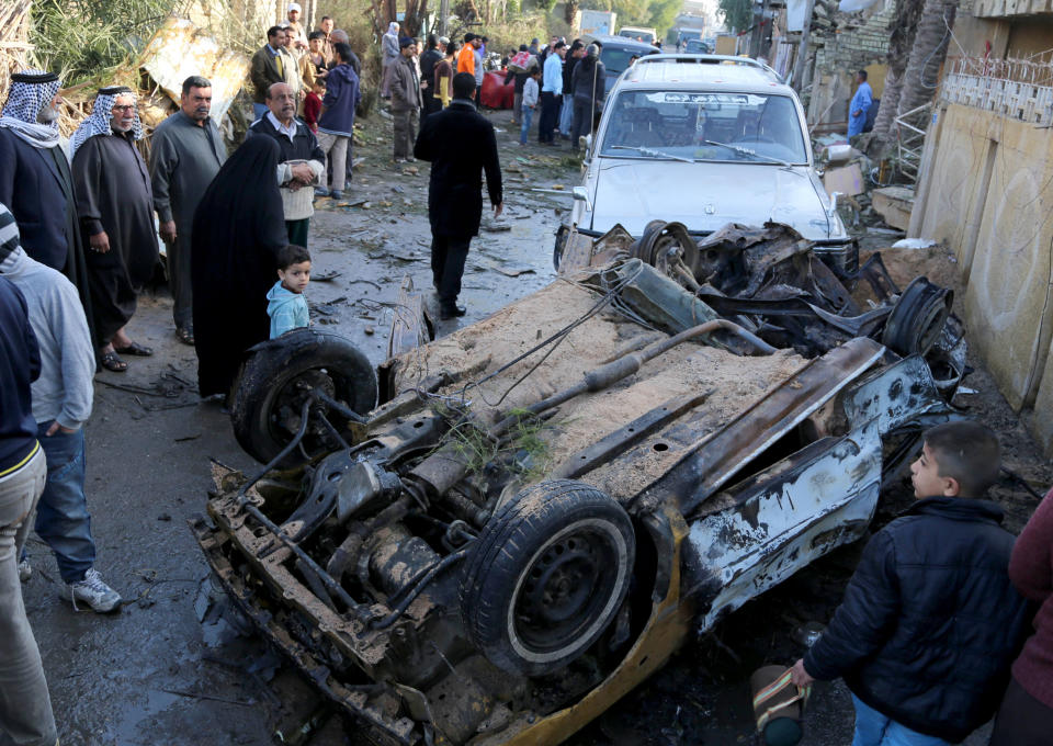 Civilians gather at the site of a car bomb attack at Shula neighborhood in Baghdad, Iraq, Thursday, Jan. 30, 2014. Car bombs and a shooting, mainly in Shiite areas, killed tens of people in the Iraqi capital on Wednesday, officials said, as authorities released a rare photograph of a man they say is the leader of al-Qaida's local branch.(AP Photo/Karim Kadim)