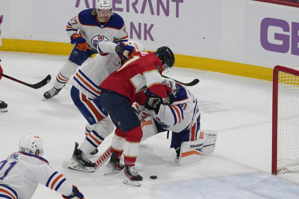 Edmonton Oilers goaltender Calvin Pickard (30) holds on to Florida Panthers center Nick Cousins' (21) stick as he tried to kick the puck into the goal during the second period of an NHL hockey game, Monday, Nov. 20, 2023, in Sunrise, Fla. (AP Photo/Marta Lavandier)