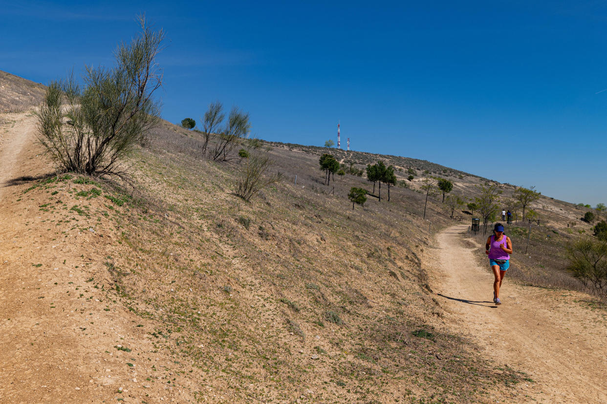 A jogger runs along a footpath surrounded by parched scrubland at the Bosque Metropolitano city forest site at Cerro Almodovar, in the Vicalvaro district of Madrid, Spain, on Tuesday, April 4, 2023. / Credit: Bloomberg