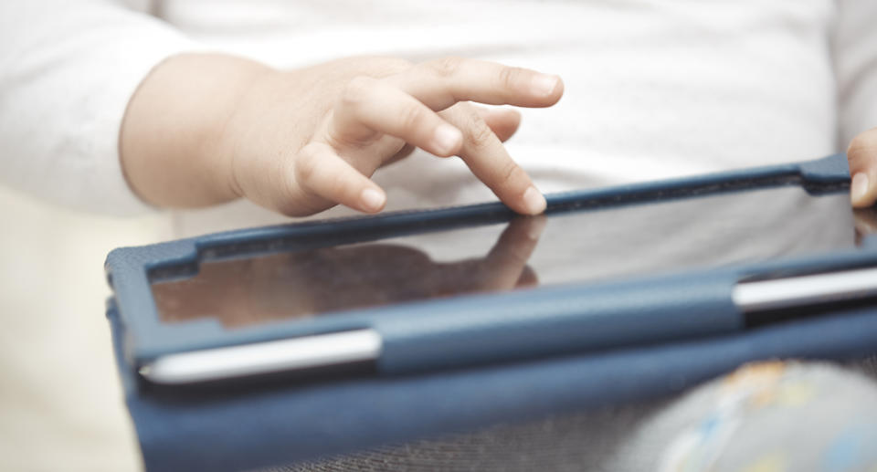 Pictured is a young child playing with a tablet.