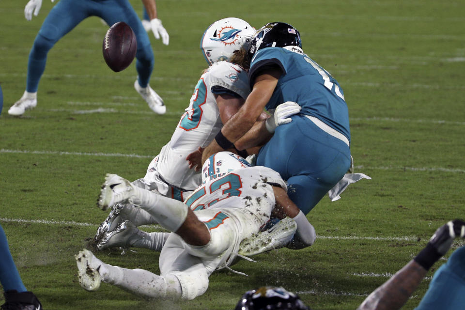 Jacksonville Jaguars quarterback Gardner Minshew, right, fumbles the ball as he is hit by Miami Dolphins outside linebacker Andrew Van Ginkel, left, and middle linebacker Kyle Van Noy during the second half of an NFL football game, Thursday, Sept. 24, 2020, in Jacksonville, Fla. (AP Photo/Stephen B. Morton)