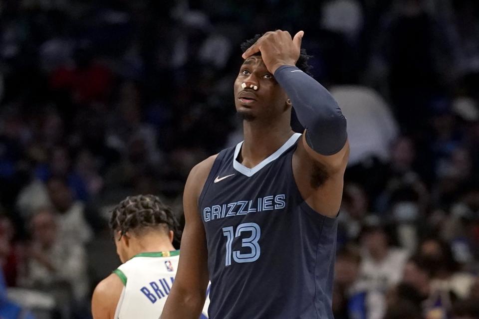 Memphis Grizzlies forward Jaren Jackson Jr. (13) wipes his forehead as he walks across the court after a play in the second half of an NBA basketball game against the Dallas Mavericks in Dallas, Sunday, Jan. 23, 2022. Jackson Jr., world gauze in his nostrils for a while after he received a blow to the face off the elbow of the Mavericks' Maxi Kleber. (AP Photo/Tony Gutierrez)