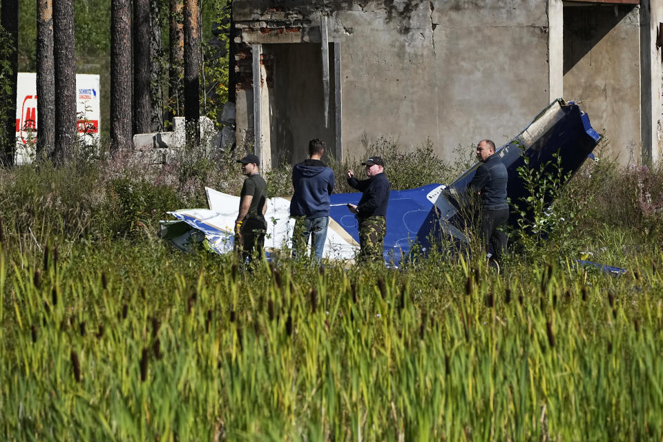 Russian servicemen inspect a part of a crashed private jet near the village of Kuzhenkino, Tver region, Russia, Thursday, Aug. 24, 2023. Russian mercenary leader Yevgeny Prigozhin, the founder of the Wagner Group, reportedly died when a private jet he was said to be on crashed on Aug. 23, 2023, killing all 10 people on board. (AP Photo/Alexander Zemlianichenko)