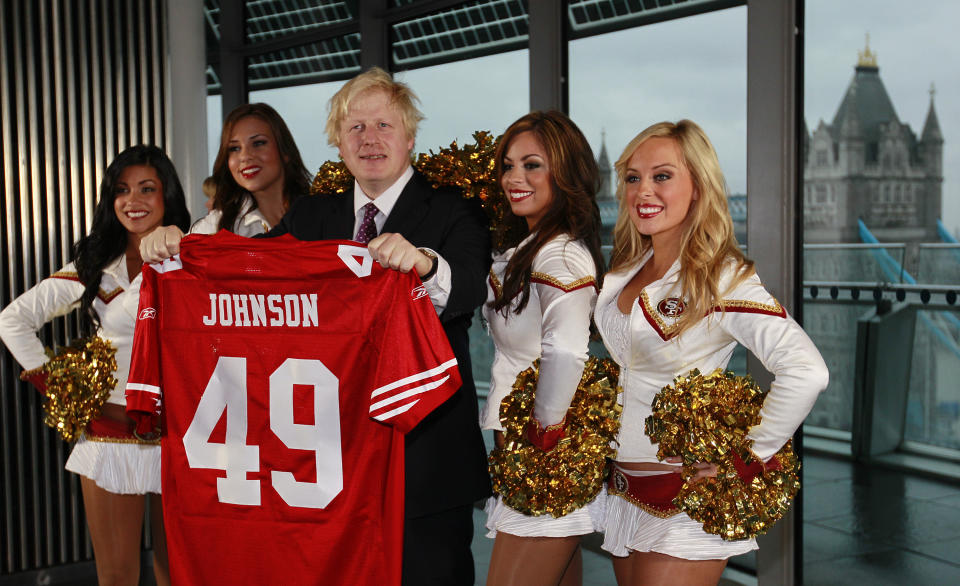 FILE - In this Tuesday, Oct., 26, 2010 file photo Boris Johnson, then Mayor of London center, and four of the 49ers cheerleaders Deanna Ortega, left, Morgan McLeod, Alexis Kofoed and Lauren Riccaboni, right, pose for the media as the Mayor holds a team shirt with his name on at City Hall in London. (AP Photo/Alastair Grant)