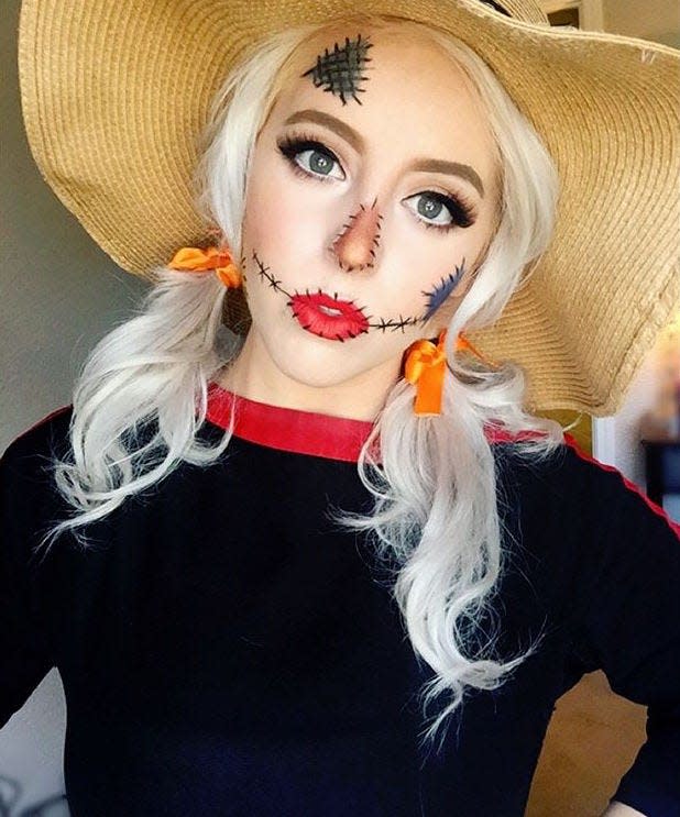 A woman wearing scarecrow makeup and a straw hat