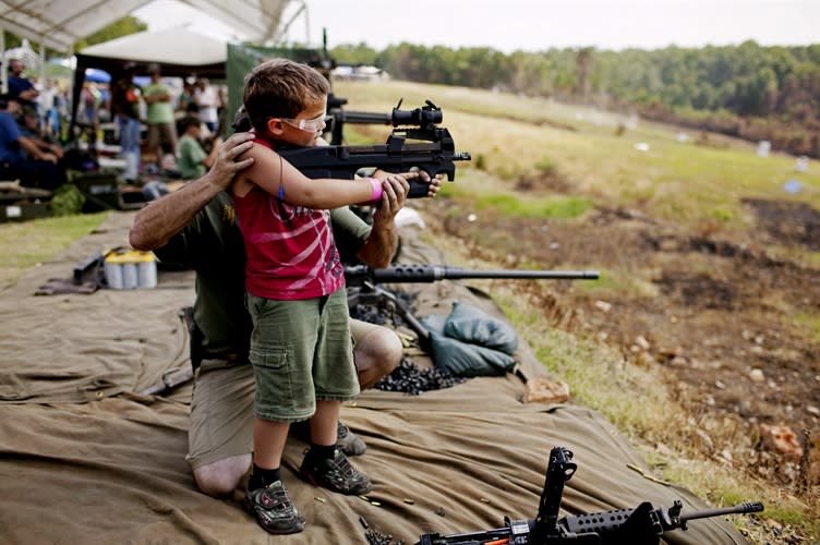 <div class="caption-credit"> Photo by: Pete Muller</div>United States photographer Pete Muller found this young boy getting help firing a fully automatic machine gun at the OFASTS gun shoot. <br> <br>