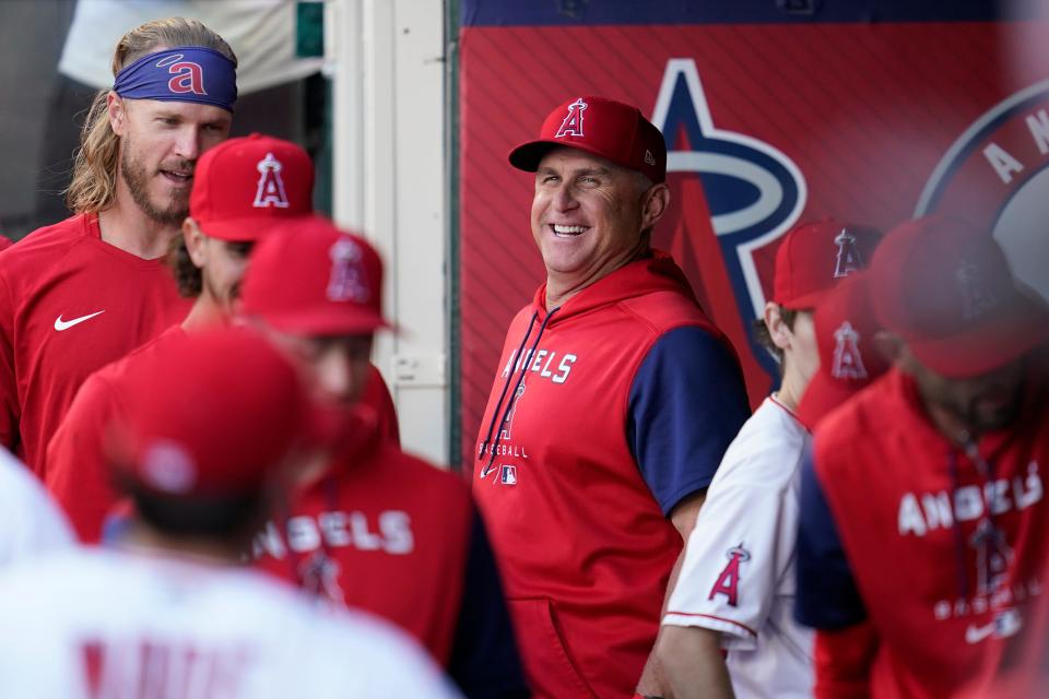 Los Angeles Angels interim manager Phil Nevin, center, smiles in the dugout before a baseball game against the Boston Red Sox in Anaheim, Calif., Tuesday, June 7, 2022. (AP Photo/Ashley Landis)