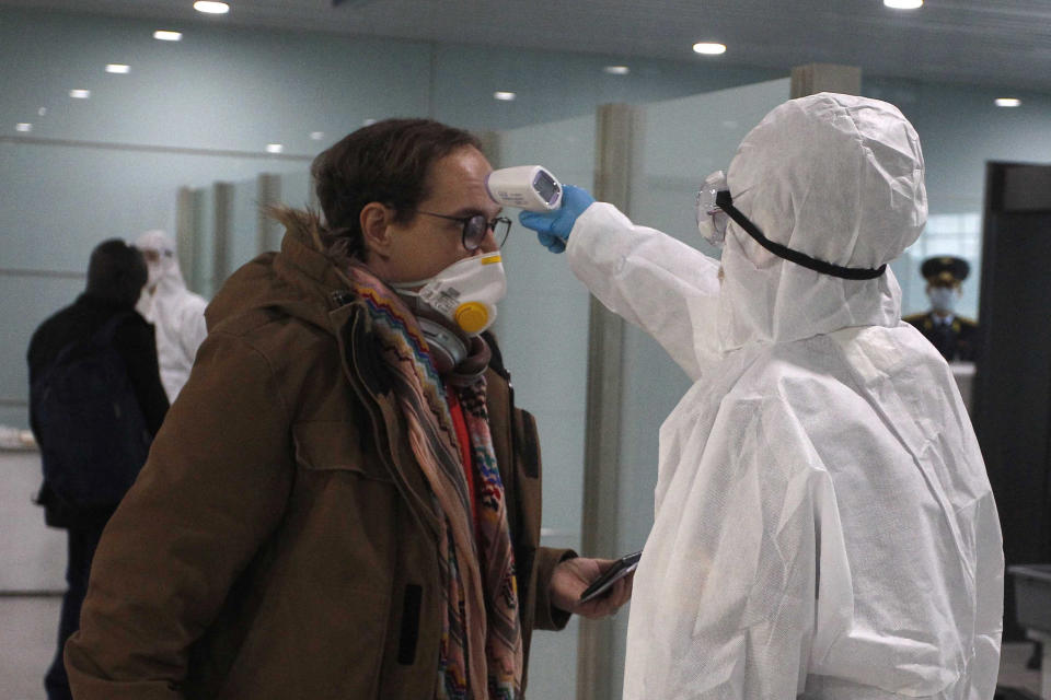 A passenger wearing a mask as a precaution against a new coronavirus has his temperature checked before boarding a flight to Vladivostok, Russia, at the Pyongyang International Airport in Pyongyang, North Korea, Monday, March 9, 2020. (AP Photo/Cha Song Ho)
