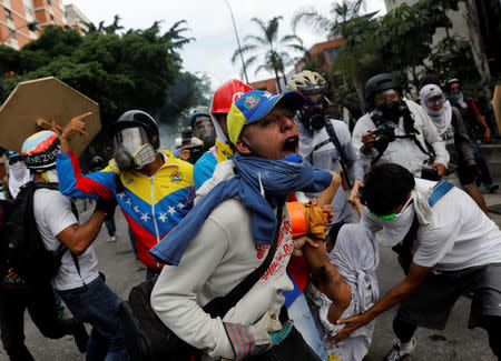 An injured opposition supporter is helped by others while clashing with riot police during a rally against President Nicolas Maduro in Caracas, Venezuela, May 3, 2017. REUTERS/Carlos Garcia Rawlins