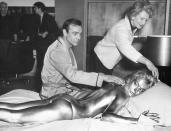 FILE - In this file photo dated April 20, 1964, James Bond, alias, Sean Connery, finds himself in a sticky situation with actress Shirley Eaton at Pinewood Studios, near London. Miss Eaton was given a liberal coating of gold paint for a scene in the latest Bond thriller "Goldfinger," with unidentified woman at top. Scottish actor Sean Connery, considered by many to have been the best James Bond, has died aged 90, according to an announcement from his family. (AP Photo/Victor Boynton)