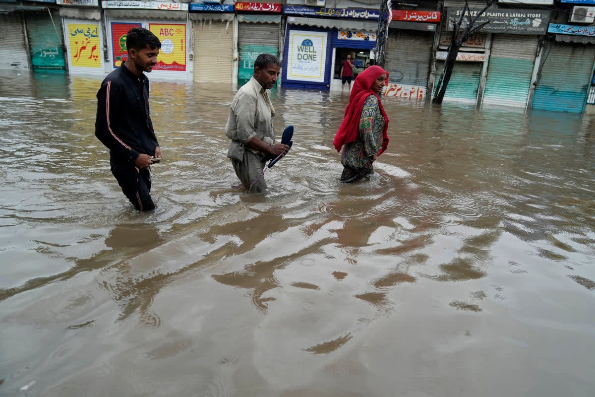 People wade through a flooded area caused by heavy monsoon rainfall in Lahore, Pakistan (AP)