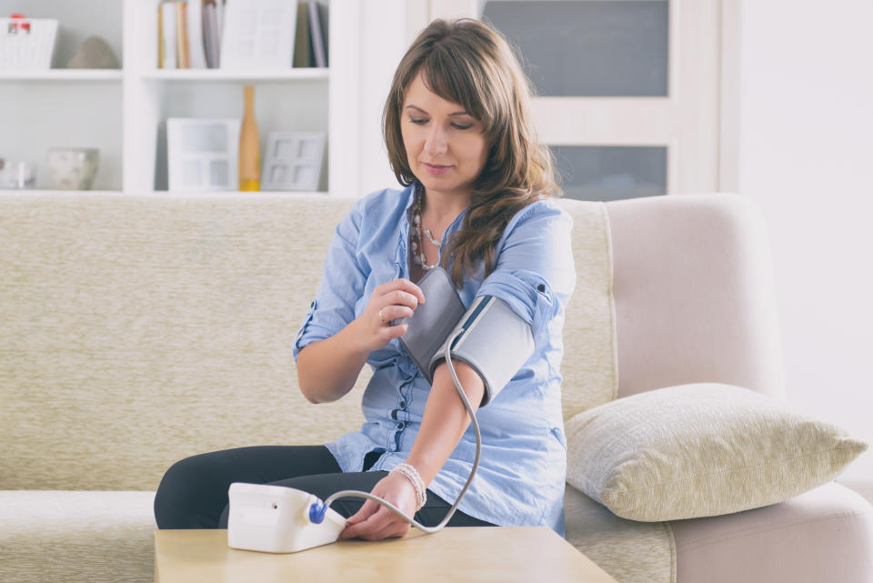 Women checking her blood pressure at home with a device.