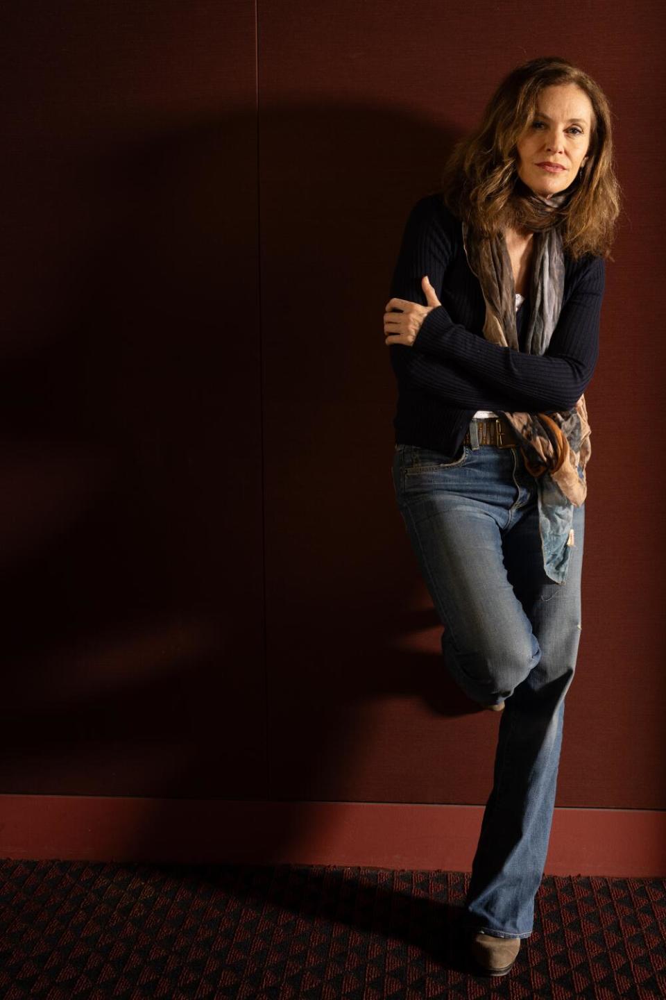 A woman standing against a wall, one leg bent to put her foot up against the wall