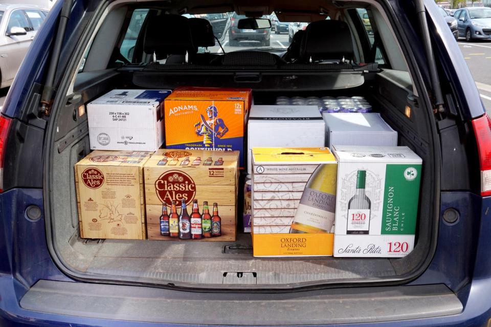 Car trunk loaded with cardboard cases of beer and wine.