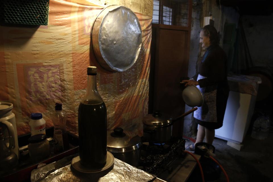 A bottle of olive oil stands on a kitchen counter as pensioner Toula Tsagaroulia looks out the front door of her home in Velanidi village, 320 kilometers (200 miles) west of Athens, Greece, on Tuesday, Dec. 3, 2013. Olive consumption in Greece has remained the highest in the world per capita despite severe household cutbacks due to the country's economic crisis. (AP Photo/Petros Giannakouris)