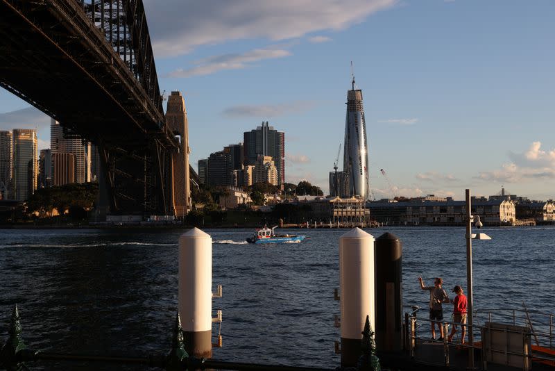 Boys fish from a pier under the Sydney Harbour Bridge in Sydney