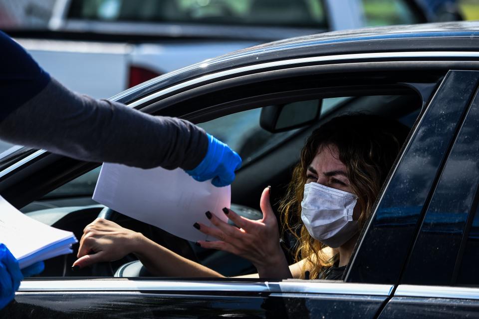 A woman collects unemployment forms at a drive-through collection point outside John F. Kennedy Library in Hialeah on April 8. (Photo: CHANDAN KHANNA/AFP via Getty Images)