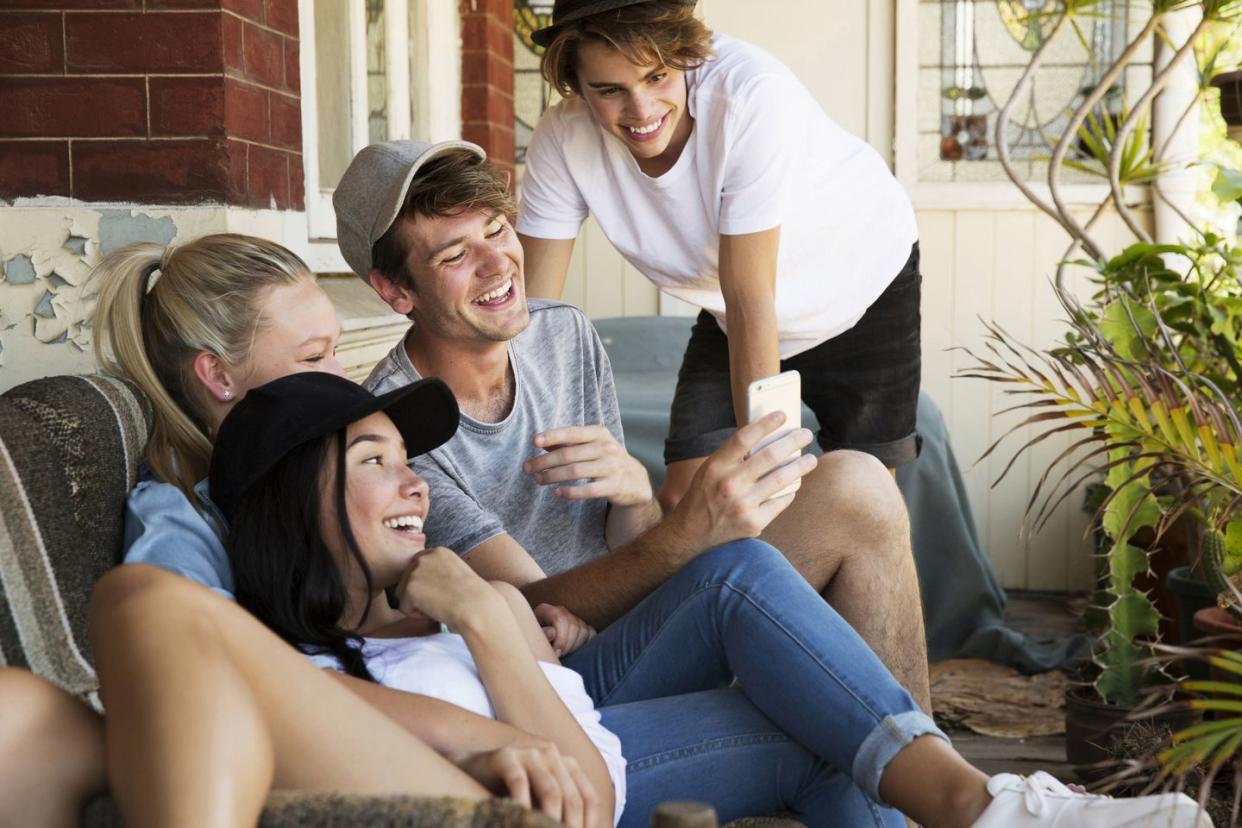 group of young adults adolescent friends on the porch of an old house