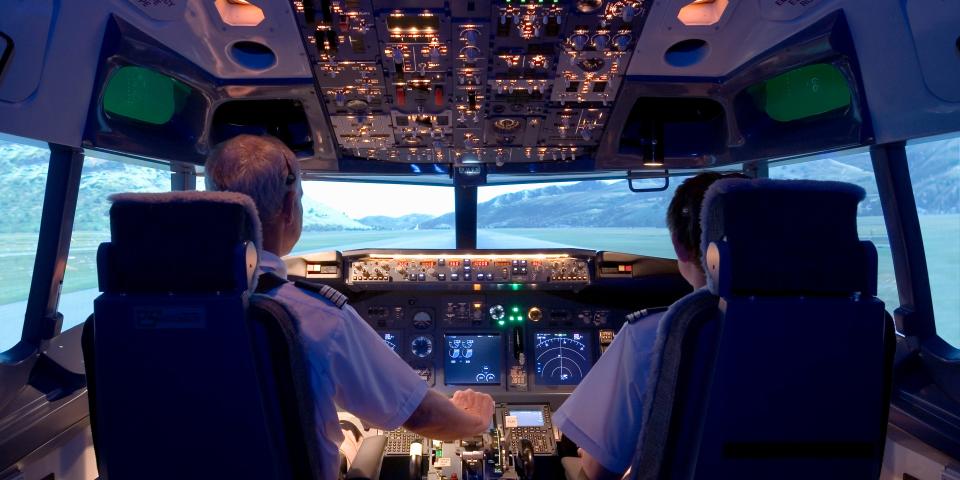 Two pilots sitting in flight simulator, rear view