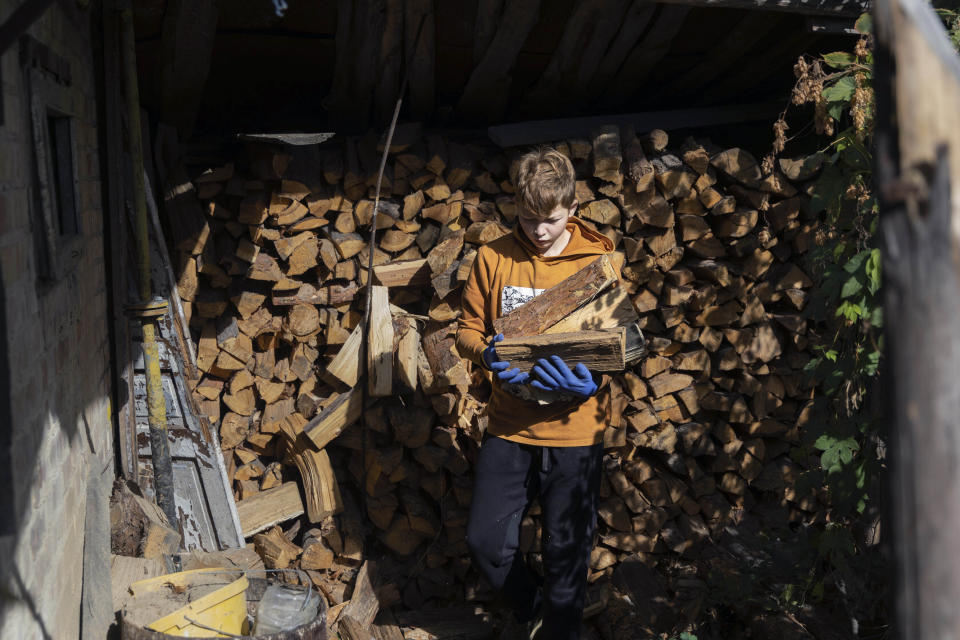 Artem Yarema, de 13 años, carga leña cerca de su casa el martes 10 de octubre de 2023, en Moshchun, cerca de Kiev, Ucrania. (AP Foto/Alex Babenko)