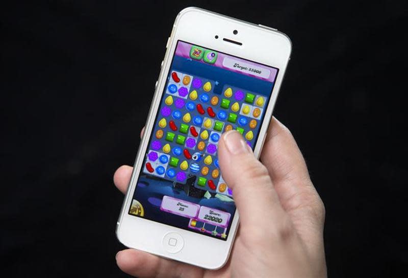 A woman poses for a photo illustration with an iPhone as she plays Candy Crush in New York February 18, 2014. REUTERS/Carlo Allegri