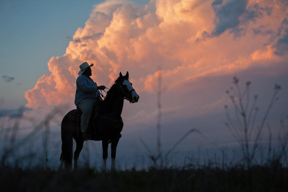 <p>Cowboy “Big Mike” Jones watches a dramatic sunset in Isola, Miss., atop his favorite horse, Lucy, March 2018. (Photograph by Rory Doyle) </p>