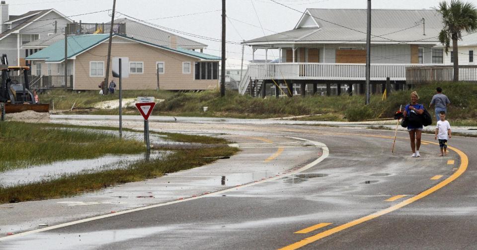 Residents carry belongings from the west end of the island as the roads are closed from 3-4 feet of sand covering the road in Dauphin Island, Ala. on Thursday, Aug. 30, 2012. Isaac dumped as much as 4 feet of sand on roads on Dauphin Island, but damage isn't bad otherwise. Mayor Jeff Collier said Thursday no homes were destroyed on the coastal barrier, even at its vulnerable western end. Crews in tractors are moving sand off the streets. Collier says conditions may have been worse without a 3.5-mile-long sand pile that was built during the BP oil spill. He says the berm helped stop sand that would have wound up on streets and in sewers without it. (AP Photo/Butch Dill)