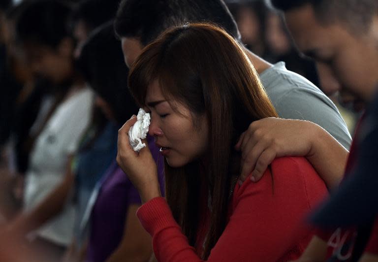 Family members of passengers onboard Malaysian air carrier AirAsia flight QZ8501 pray together inside a holding room at Juanda International Airport in Surabaya, on December 31, 2014