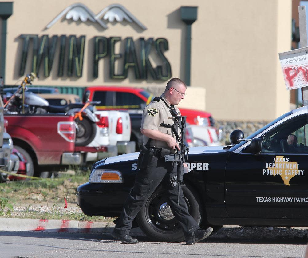 An officer secures the scene Sunday outside a Twin Peaks restaurant where a shootout left nine people dead in Waco, Texas. (Jerry Larson/AP)