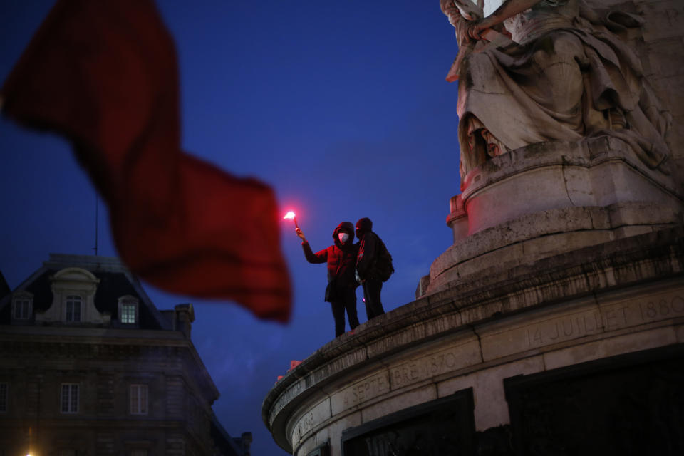 A demonstrators lights up a flare during a protest against a proposed security bill, Saturday, Dec.12, 2020 in Paris. The bill's most contested measure could make it more difficult for people to film police officers. It aims to outlaw the publication of images with intent to cause harm to police. The provision has caused such an uproar that the government has decided to rewrite it. Critics fear the law could erode press freedom and make it more difficult to expose police brutality. (AP Photo/Thibault Camus)