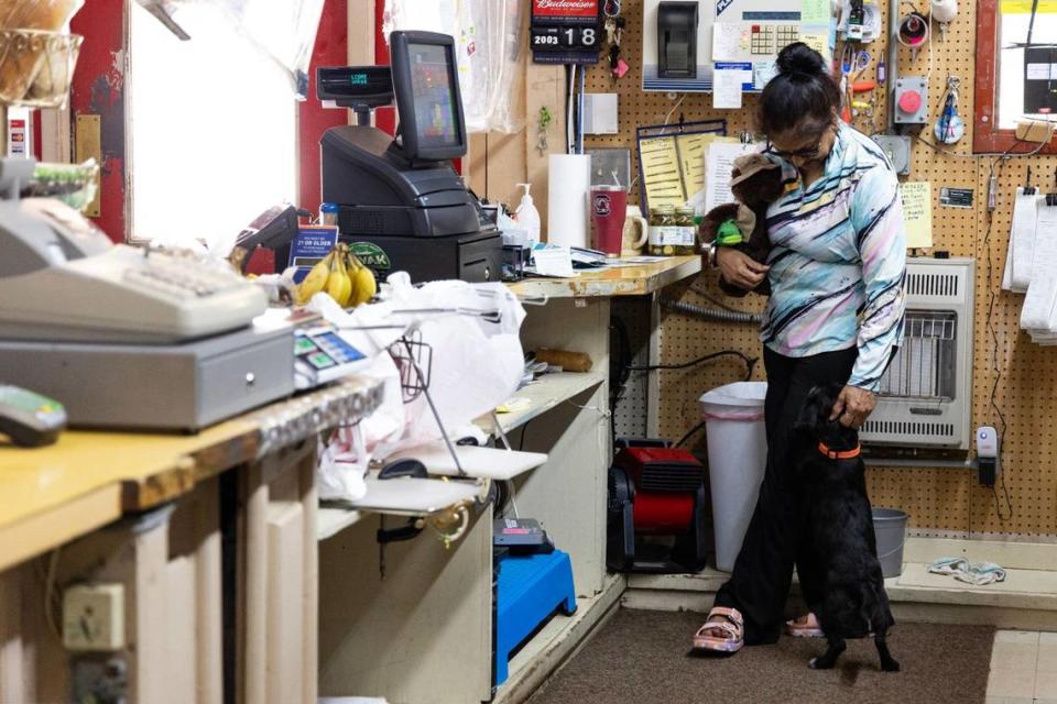 N.U. Singh pets Tippy, Hansel Carter’s dog, as she works as a cashier at Mr. Bunky’s Market, in Eastover, South Carolina on Tuesday, June 18, 2024.