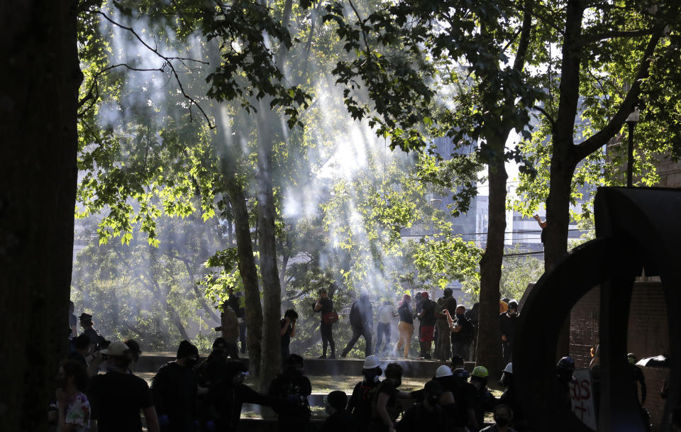 Smoke drifts through trees Saturday, July 25, 2020, at Seattle Central Community College in Seattle after police used flashbang devices to move a large group of protesters who were marching in support of Black Lives Matter and against police brutality and racial injustice. (AP Photo/Ted S. Warren)