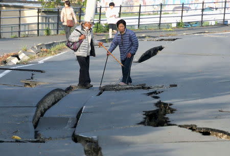 Local residents look at cracks caused by an earthquake on a road in Mashiki town, Kumamoto prefecture, southern Japan, in this photo taken by Kyodo April 16, 2016. REUTERS/Kyodo