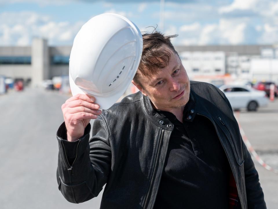 Elon Mush holds a Tesla-branded hard hat.
